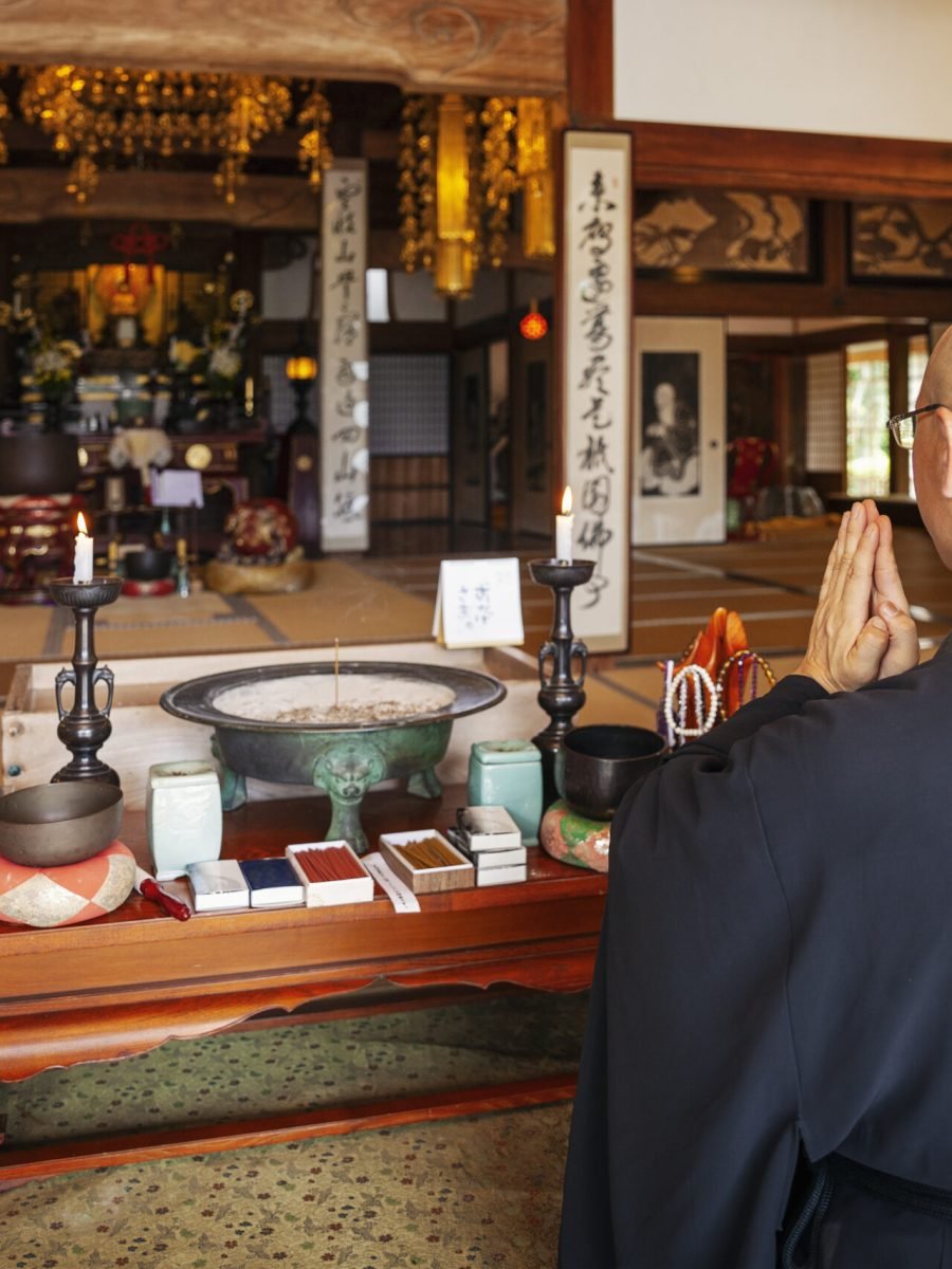 Buddhist priest kneeling in Buddhist temple, praying.
